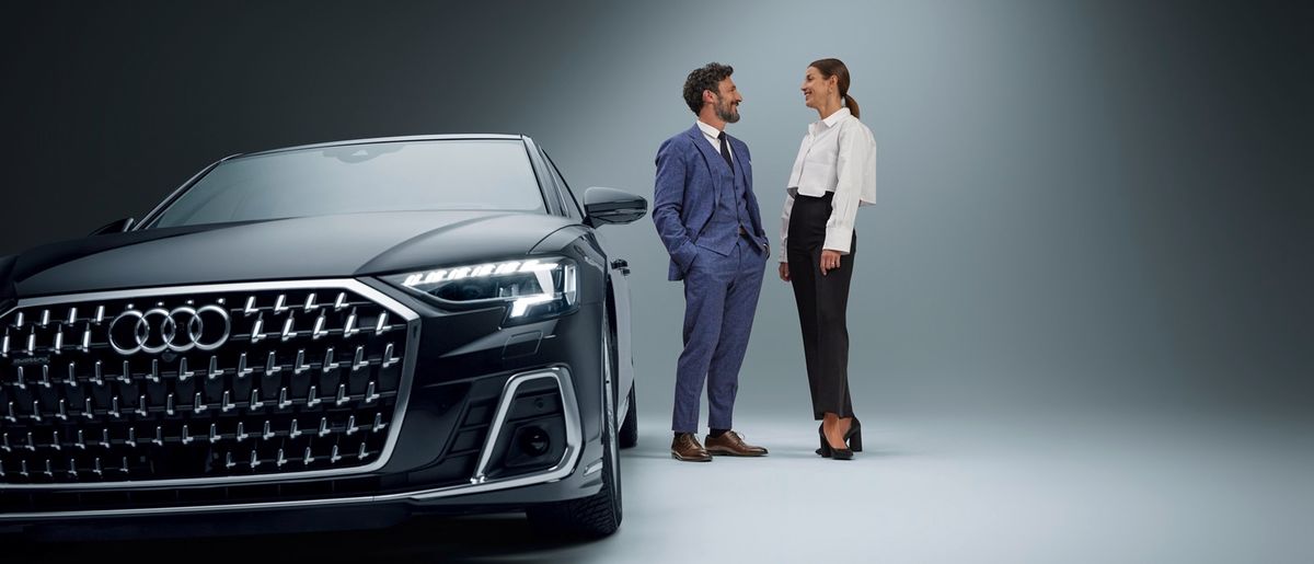 Two businessmen talking in front of a car