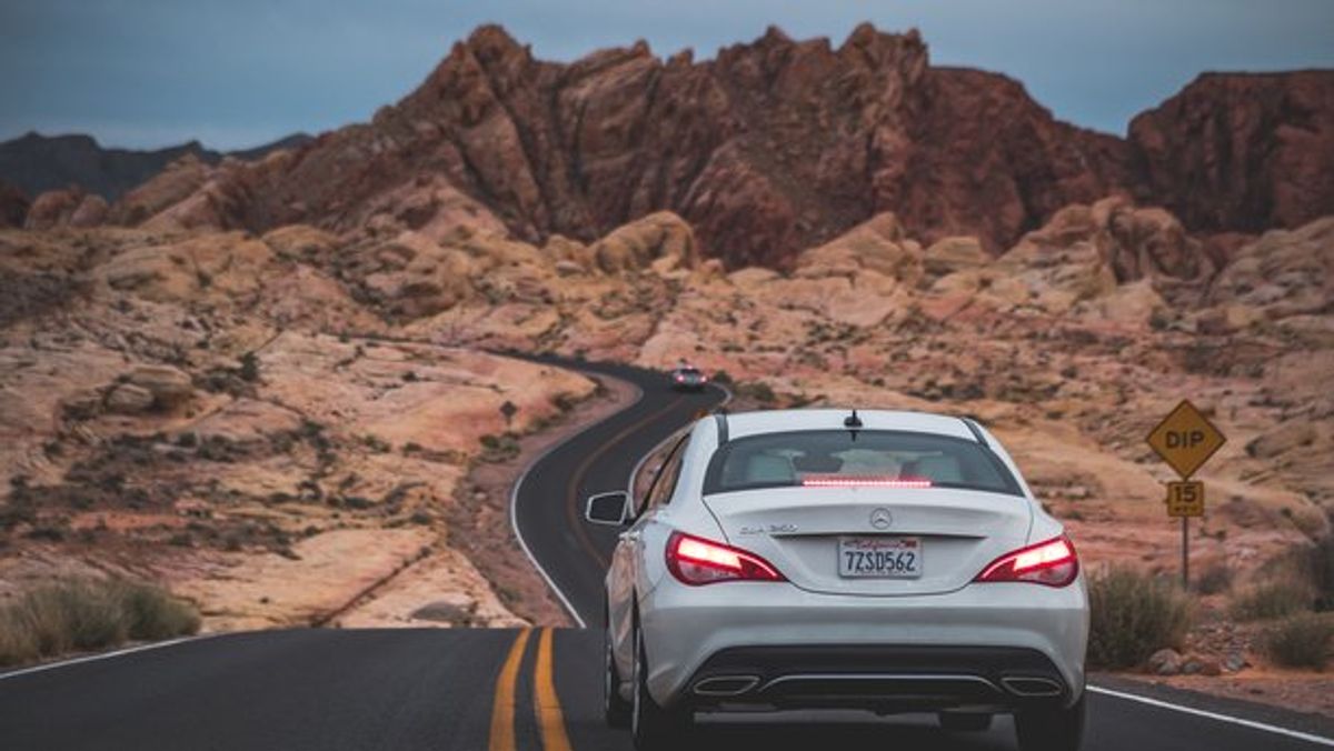 White car on US road desert for one way car rental